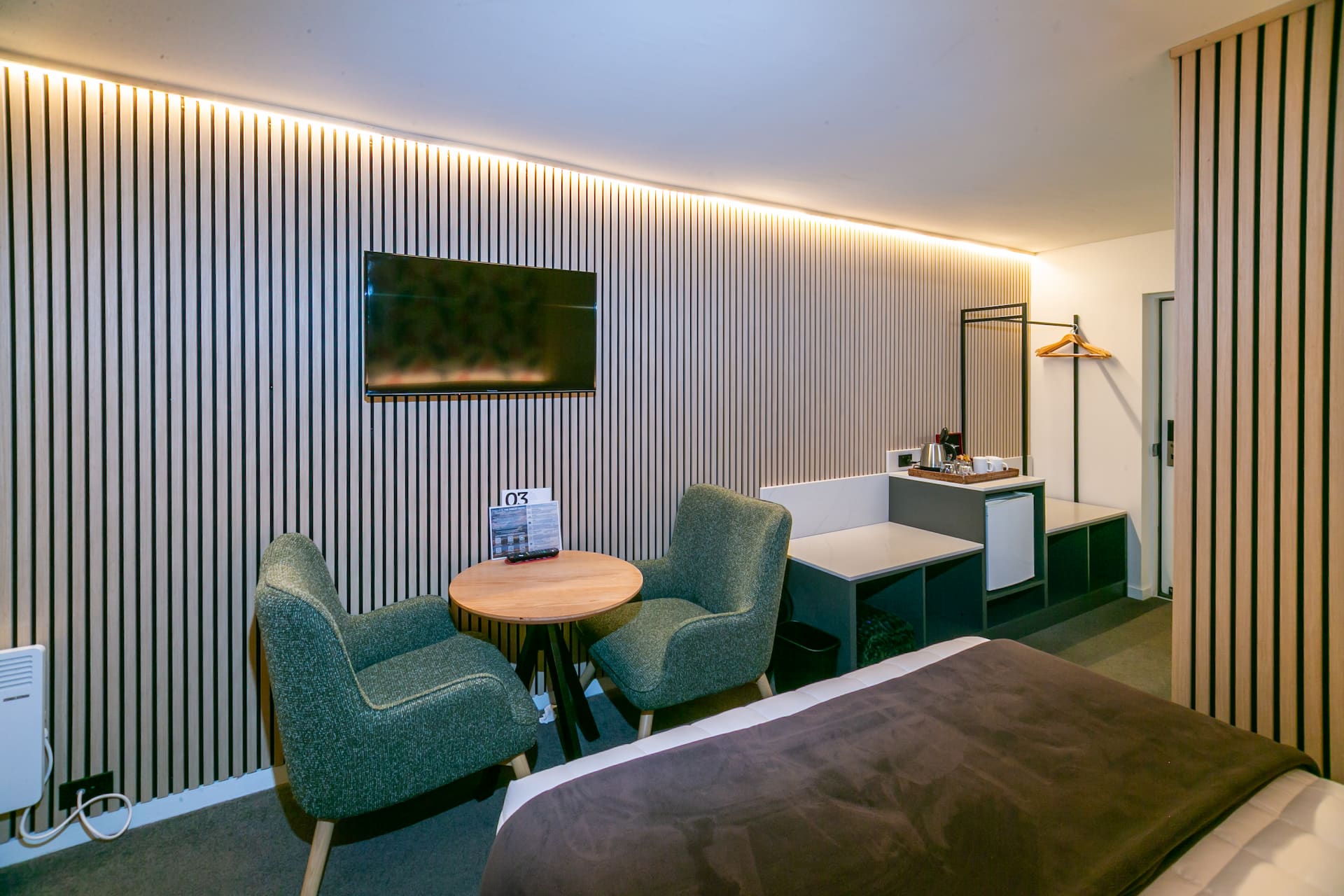 Guest room seating and slatted wall joinery at The Godley Hotel